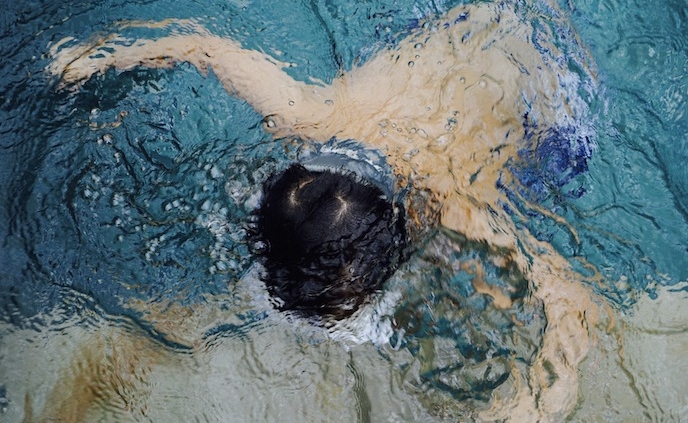 Shows a young boy in a pool face down in the water