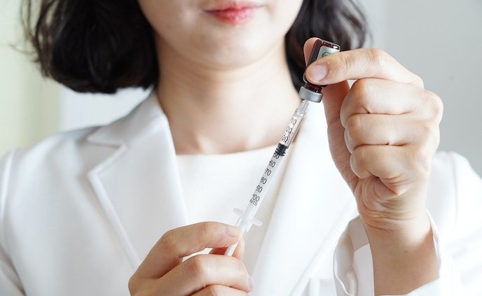 Shows an image of an Asian doctor/nurse filling a syringe