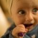 Shows a baby gnawing a small toy