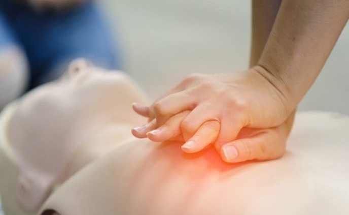 Shows two clasped hands performing CPR on a CPR mannequin