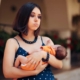 Shows a young mother in a blue dress looking tired and overwhelmed while holding a small baby